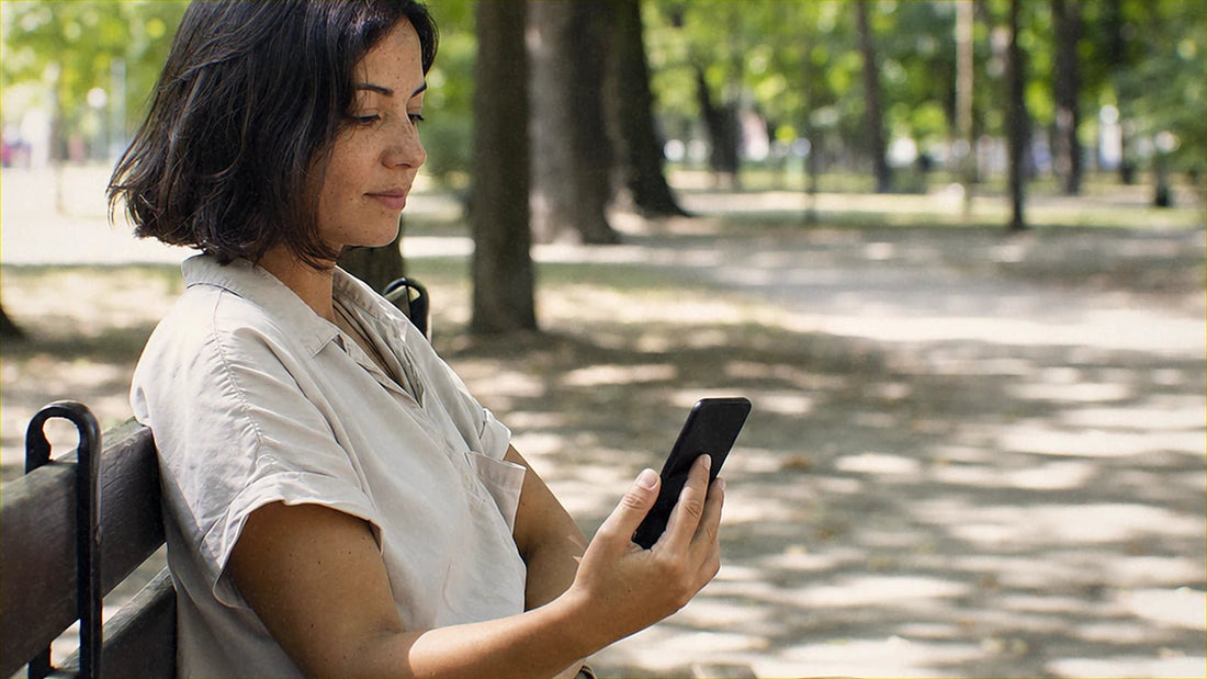 都市公園のベンチに座ってスマホを操作している人です。